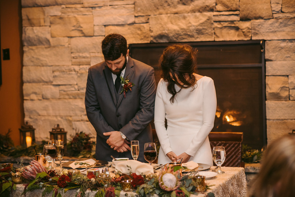 Lake Tahoe Wedding Planners couple praying by table with La Tavola Mika Champagne linen at venue The Resort at Squaw Creek, Lake Tahoe, Joy of Life Events image by Charleston Churchill